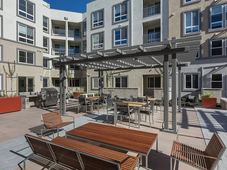 Outdoor dining area with BBQ stations and shaded seating at Aster Apartments in Dublin, CA.