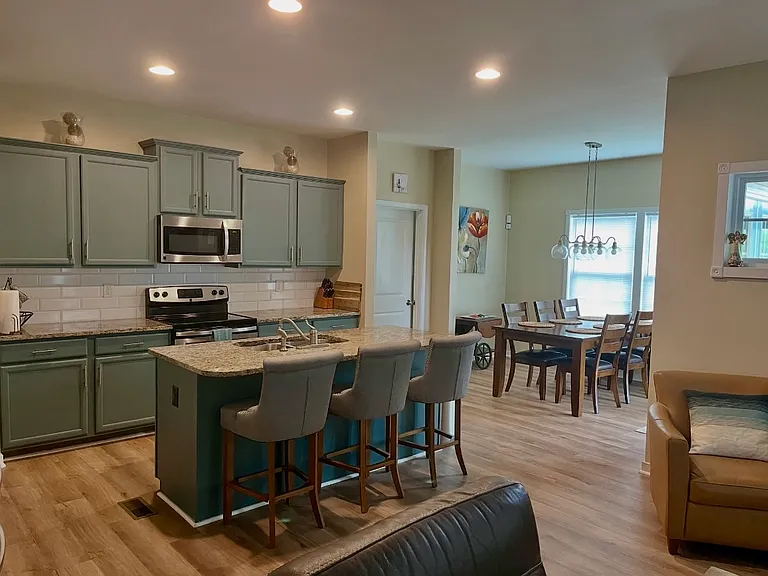 Open layout kitchen with 3 barstools & eat in nook with 6 person dining table