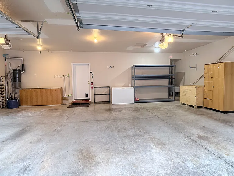 Spacious three-car garage featuring extensive storage & cabinetry, and a utility sink for added convenience.