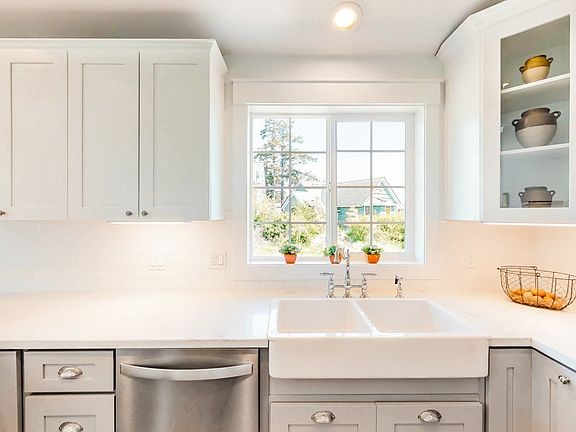 Clean and simple kitchen with farmhouse sink, ss appliances and hardwood flooring.