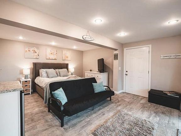 Large bright room with recessed lighting, fridge, laminate flooring, 2 deck sliders to lanai