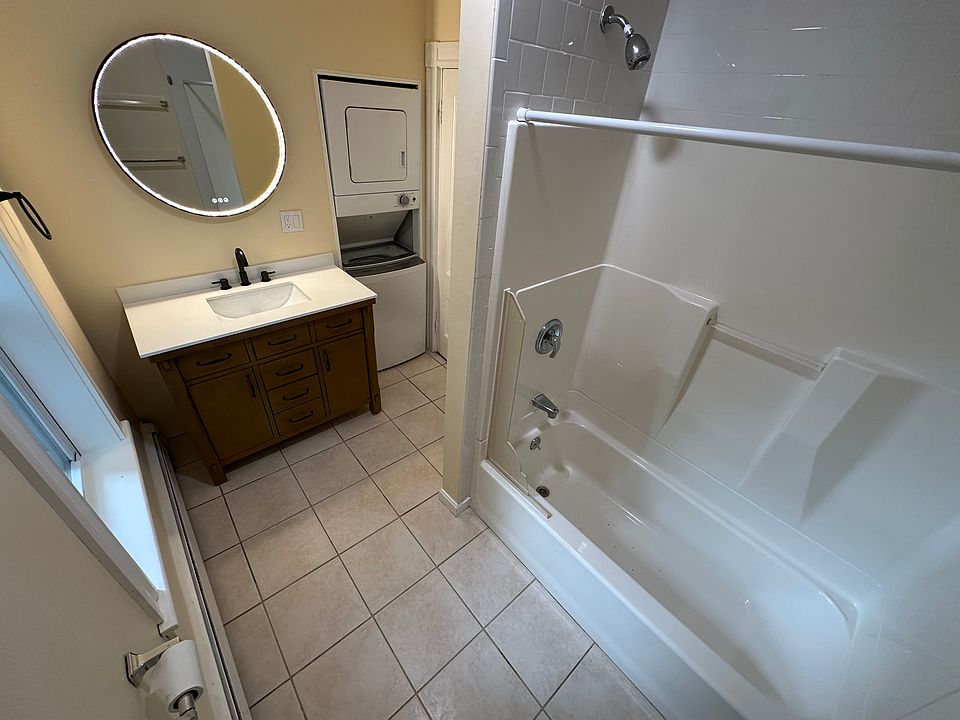 Updated bath with LED mirror and stacked washer/dryer in unit.