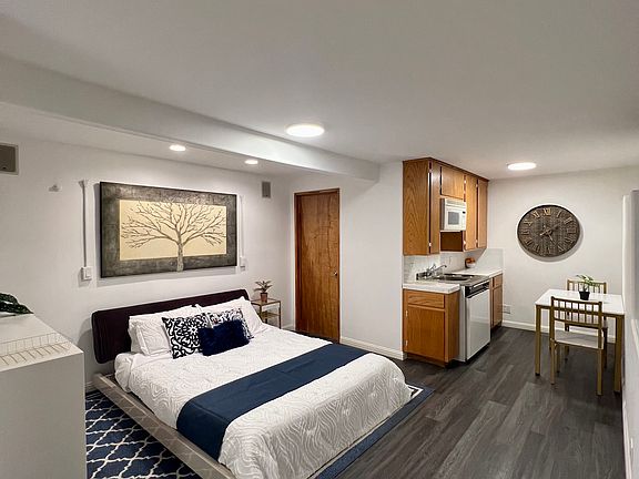 Main living area with queen size bed, dresser, and kitchenette.