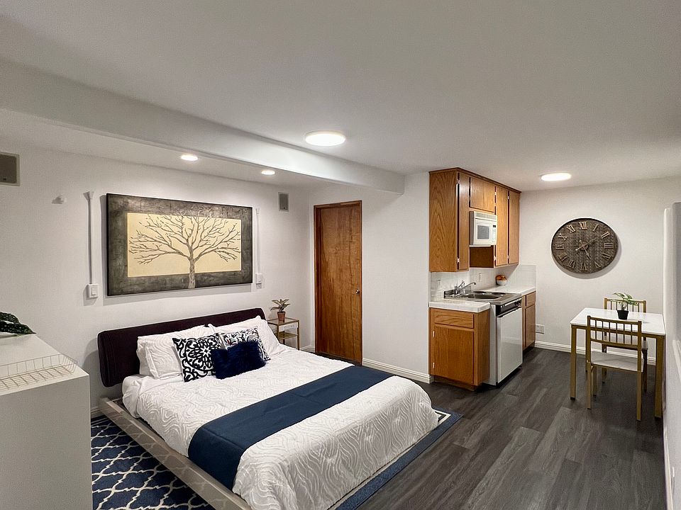 Main living area with queen size bed, dresser, and kitchenette.