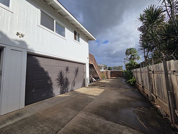Single lane driveway looking towards street with entrance gate closed.