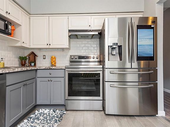 Beautifully updated granite kitchen countertops, tile backsplash, and two-toned cabinets.