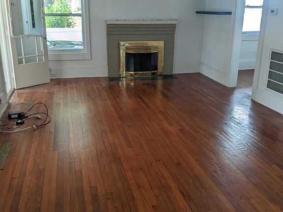 Living room hardwood floor, outside window is carport.