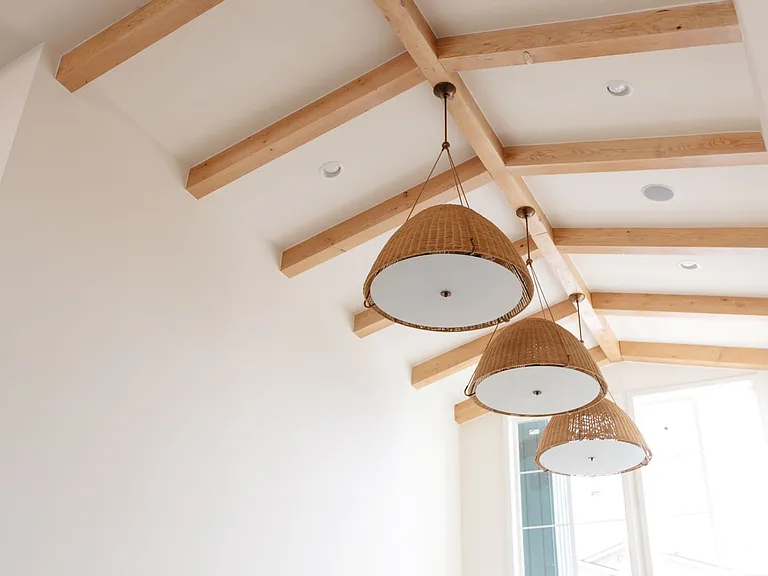 Vaulted ceiling with woven pendant lights in the clubhouse at The Elowen in Lacey, WA. Modern lighting and exposed beams bring warmth and character to this future resident gathering space.