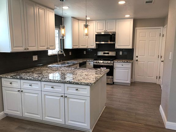 Recently updated designer kitchen with large granite peninsula, pendant lighting