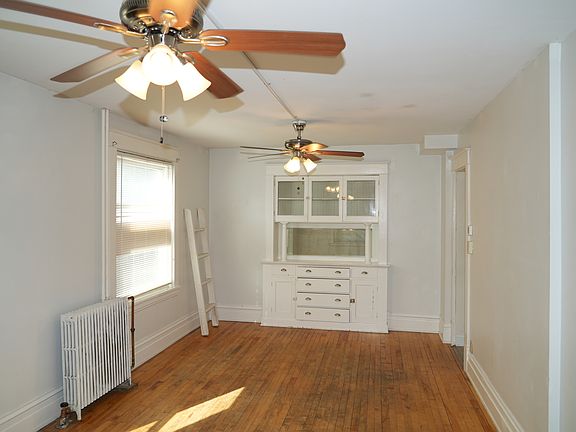 Large living room with two ceiling fans and tall windows for great light.