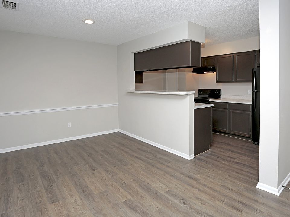 View of open dining area leading into a galley kitchen with bar-height counter and dark wood cabinets.