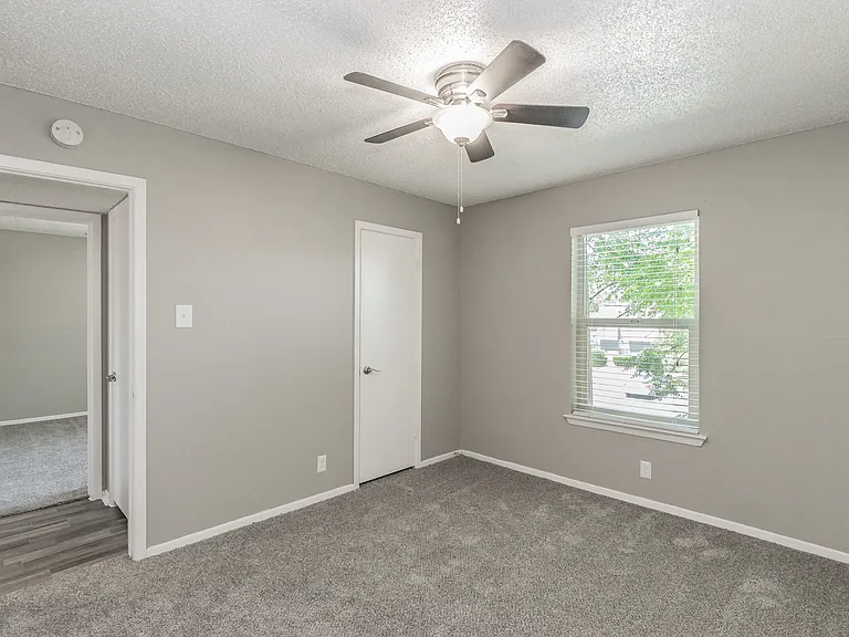Comfortable bedroom with ceiling fan and soft carpeting