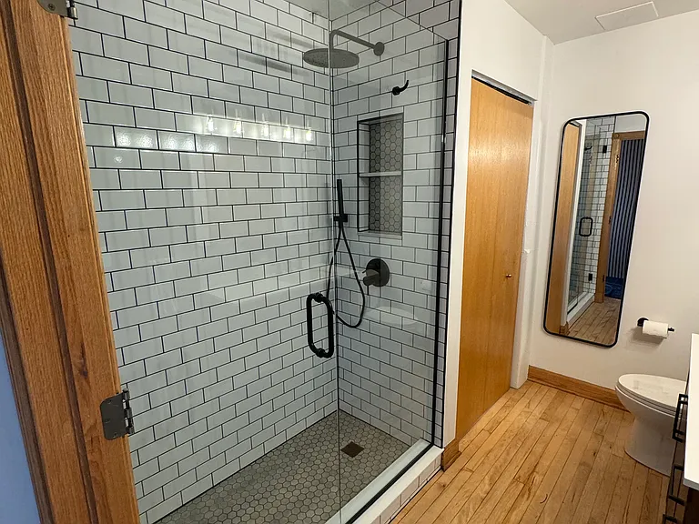 Large custom walk-in tile shower with two shower heads, shampoo niche, towel hook, and glass shower door that swings both ways. Washer/Dryer behind closet doors