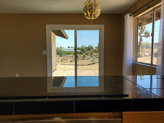 View from the kitchen of the diningroom. Sliding patio door opens to the patio. Electric cooktop in the foreground has multiple layer safety features which allow it to be used as addional counter space. This is a great hub for dining and entertaining.