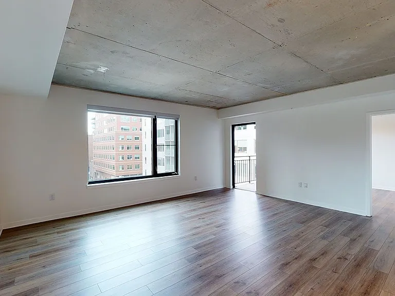 Apartment living room with wood-style flooring and balcony or patio in select homes.