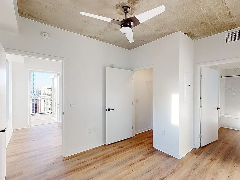 Spacious apartment bedroom with large closet and wood-style flooring.