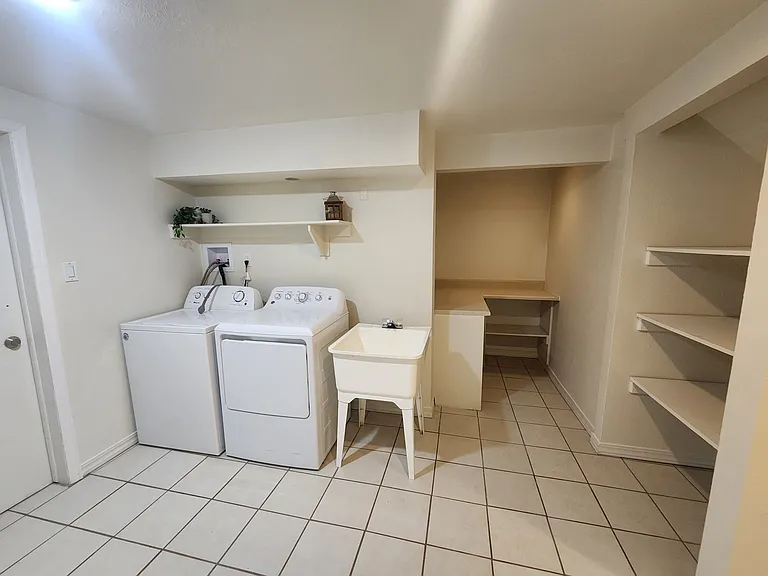 Large basement laundry room with plenty of shelving and hanging storage.