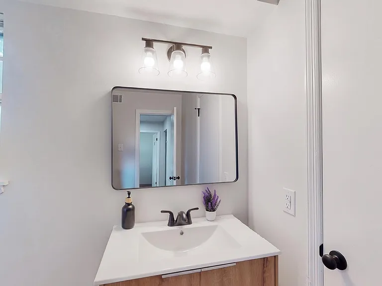 Updated vanity area features a wide mirror, modern lighting, and a spacious countertop with convenient storage below.
