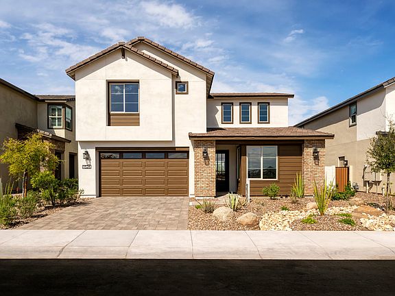 A two-story residential house with a garage, surrounded by landscaped gardens and a clear blue sky i