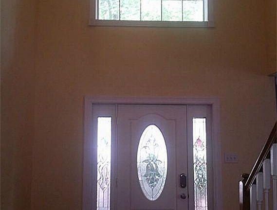 VIEW OF FRONT ENTRY WAY FROM INSIDE HOUSE. HIGH CEILINGS AND WINDOW LET IN NATURAL LIGHT