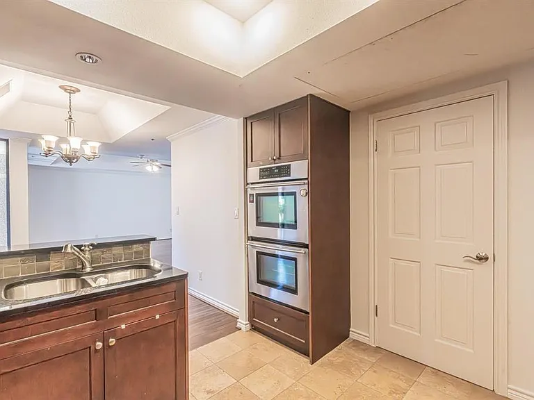 Kitchen features a double basin stainless steel sink, dark wood cabinetry, and a dark stone-finish countertop with a tiled backsplash
