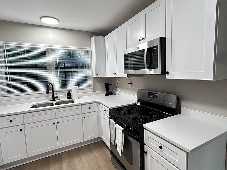 Updated kitchen with shaker cabinetry, generous counter space, and stainless steel range and microwave plus a large window.