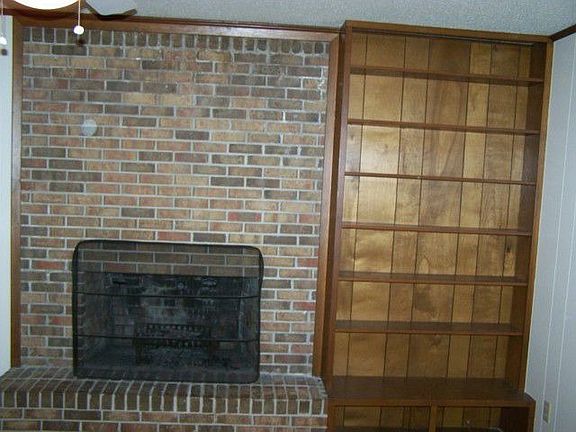 BRICK FIREPLACE AND HEARTH IN FAMILY ROOM NOTE BOOKCASES
