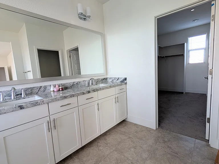 Experience ultimate convenience in this luxurious master suite. The bathroom vanity flows seamlessly into an expansive private walk-in closet, ensuring your morning routine is organized, efficient, and effortlessly elegant.