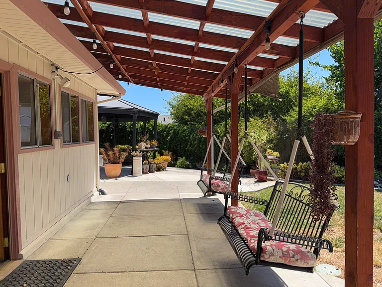 Covered pergola with porch swing and string lights for year-round outdoor lounging