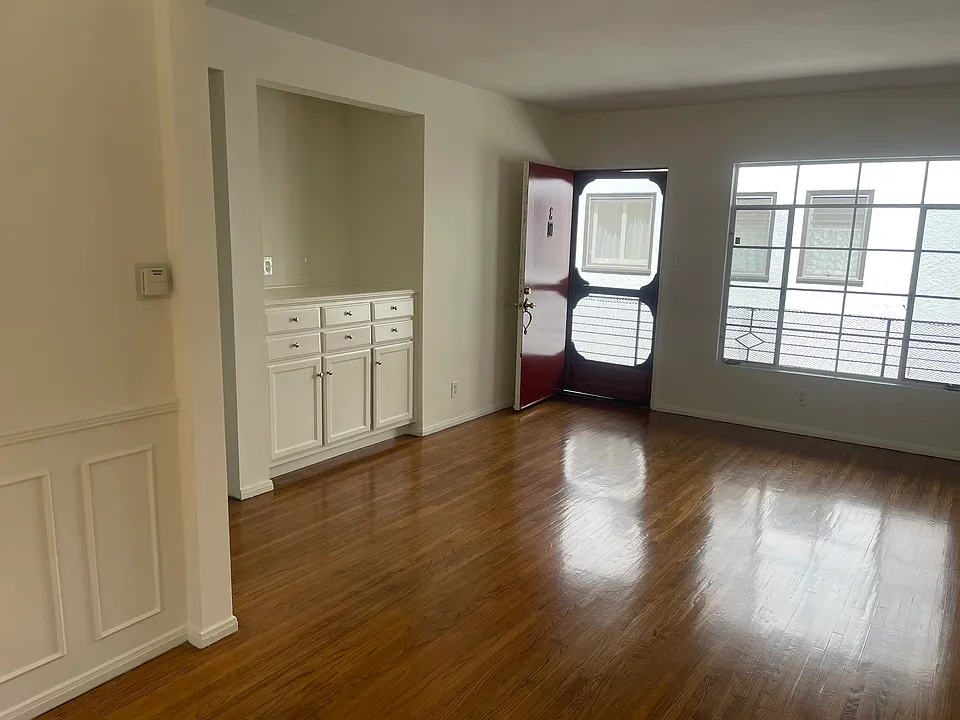 Another view of living room, front door, entertainment space, and window