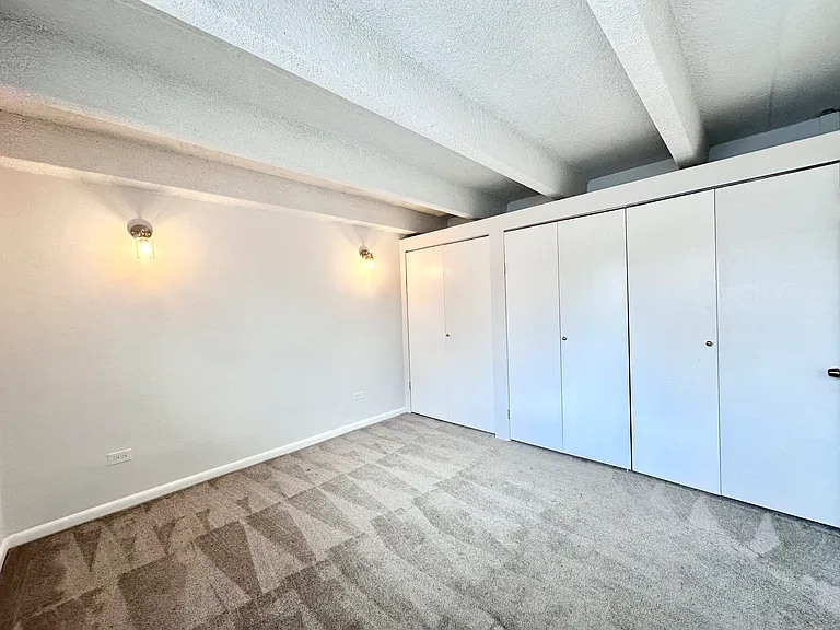 Bright and inviting bedroom with plush carpet, built-in closets, and ambient wall lighting. Bright and inviting bedroom with plush carpet, built-in closets, and ambient wall lighting.