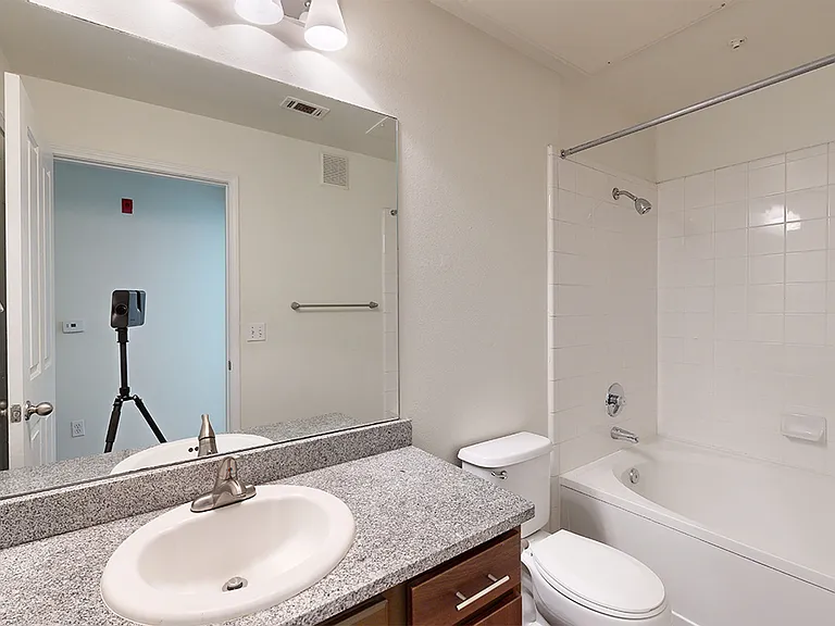 Apartment bathroom with large soaking tub and wood-style flooring.
