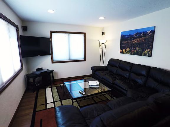 Living room with wall mount tv and wrap around leather couch.