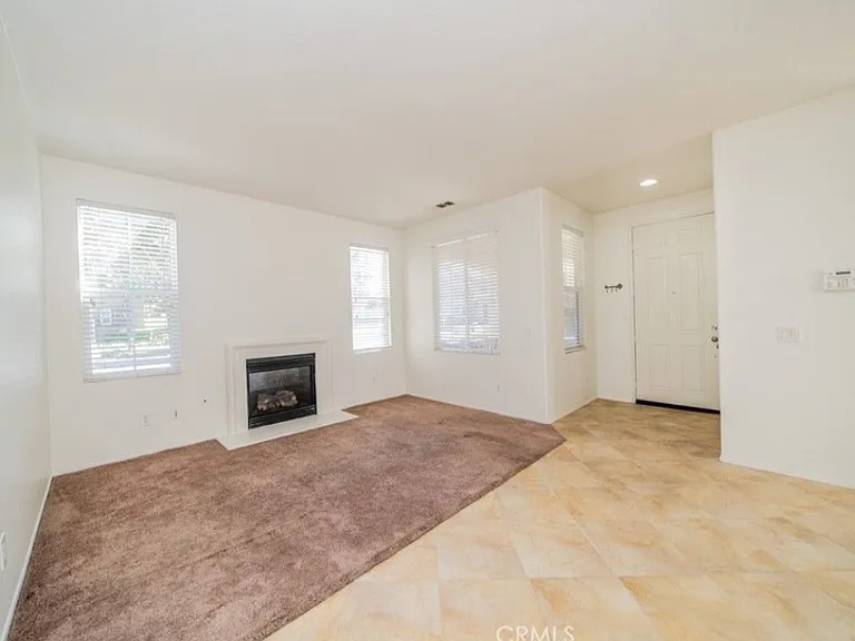 This picture shows the living room area with a cozy gas fireplace and the front door. There is also a walk in pantry by the front door. Please note: Home has been upgraded with new carpet that is not shown in this picture.