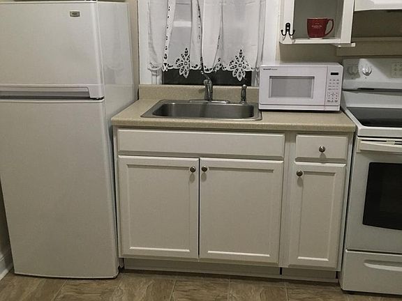 Small kitchen has fridge, stove, and microwave.