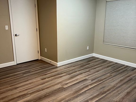 Bedroom 2 with south-facing garden-level window and ceiling fan. Solid-core door.
