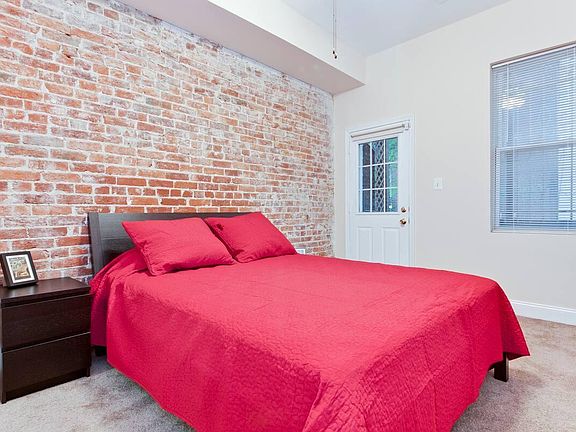 Bedroom with exposed bricks - access to balcony/backyard and the walk-in closet that connects to the bathroom on the opposite side.