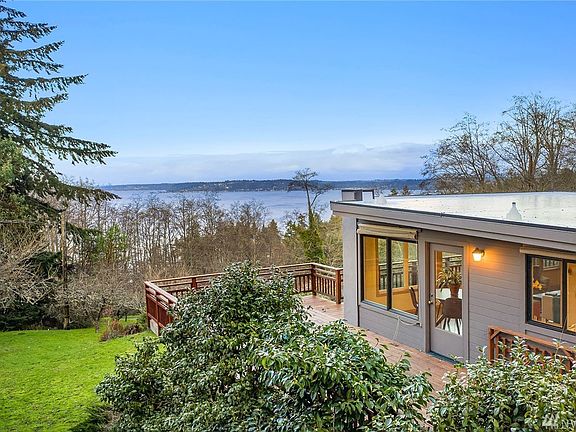 Mature landscaping and trees provide elegance and privacy. Orchard can be seen to the left below the home.