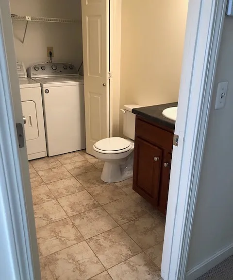 First floor half bath with tile flooring and convenient in unit laundry designed for everyday use.