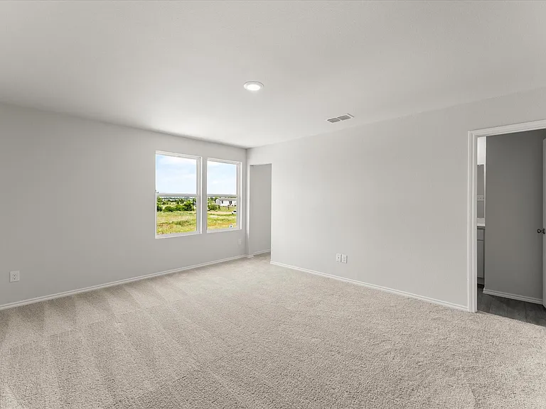 Primary bedroom featuring neutral carpeting, two large windows, recessed lighting, and a white interior door