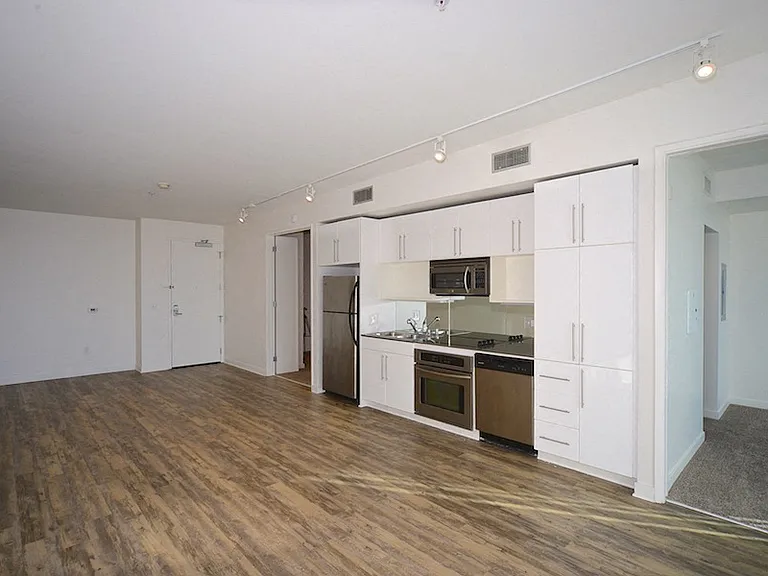 Large living room with open kitchen and two carpeted bedrooms at 12th Street Lofts in National City, California.