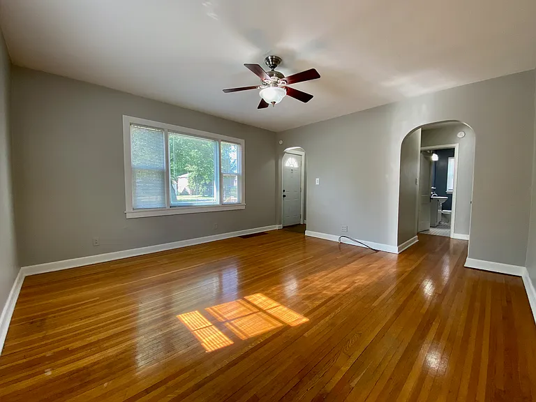 Bright and inviting living room with polished hardwood floors, a ceiling fan, and arched doorways, offering a cozy and elegant ambiance. Bright and inviting living room with polished hardwood floors, a ceiling fan, and arched doorways, offering a cozy and