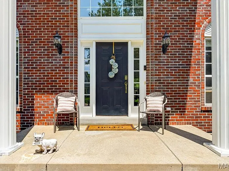 Brick exterior featuring a paneled front door with sidelights, transom window, and architectural columns