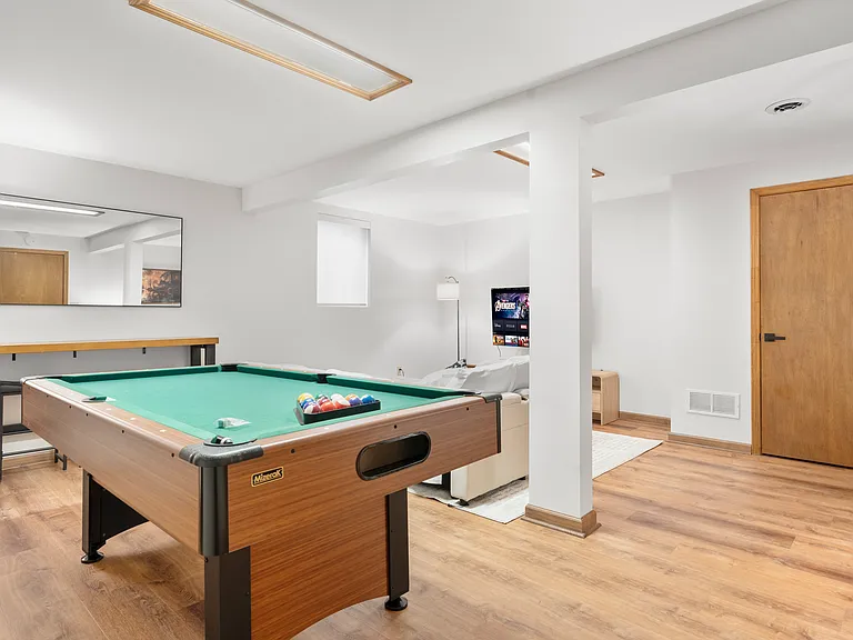 Flexible basement bedroom/lounge with a convertible sofa for comfortable seating or sleeping with pool table.
