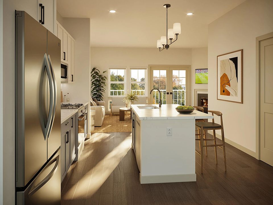 Light-filled kitchen with a quartz-topped island, streamlined cabinetry, and sightlines that connect cooking, dining, and living areas.