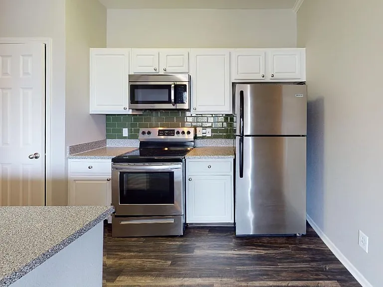 Apartment kitchen with granite countertops and wood-style flooring.