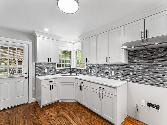Kitchen featuring white cabinets, under cabinet range hood, backsplash, dark wood-style floors, and recessed lighting