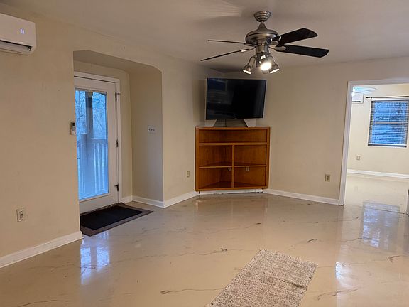 Huge living room with epoxy floors. Mini split HVAC and large flatscreen TV with entertainment center