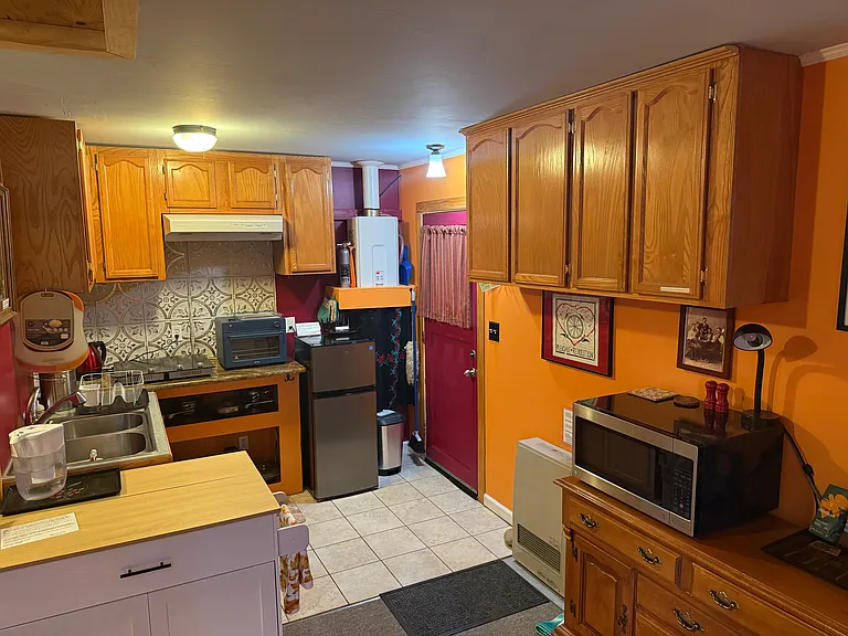 This photo shows the front door, on-demand water heater to the left, natural gas heater to rt of door, microwave. Med- sml fridge (i have a second one should you need, every tenant so far has liked this one. Lots of storage and kitchen gear.