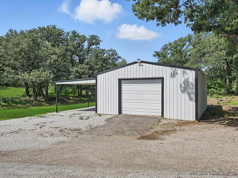 Garage with a detached garage and gravel driveway